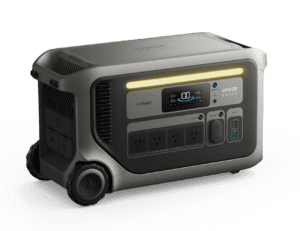 Showing the Anker SOLIX F3000 portable power station from the front angle with LED light bar, LCD display, AC outlets, USB-C, USB-A, DC outputs, rear AC outlets and integrated transport wheels.